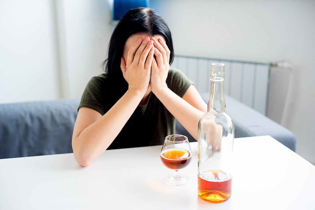 woman with hands over her face worried about detox from alcohol in front of her