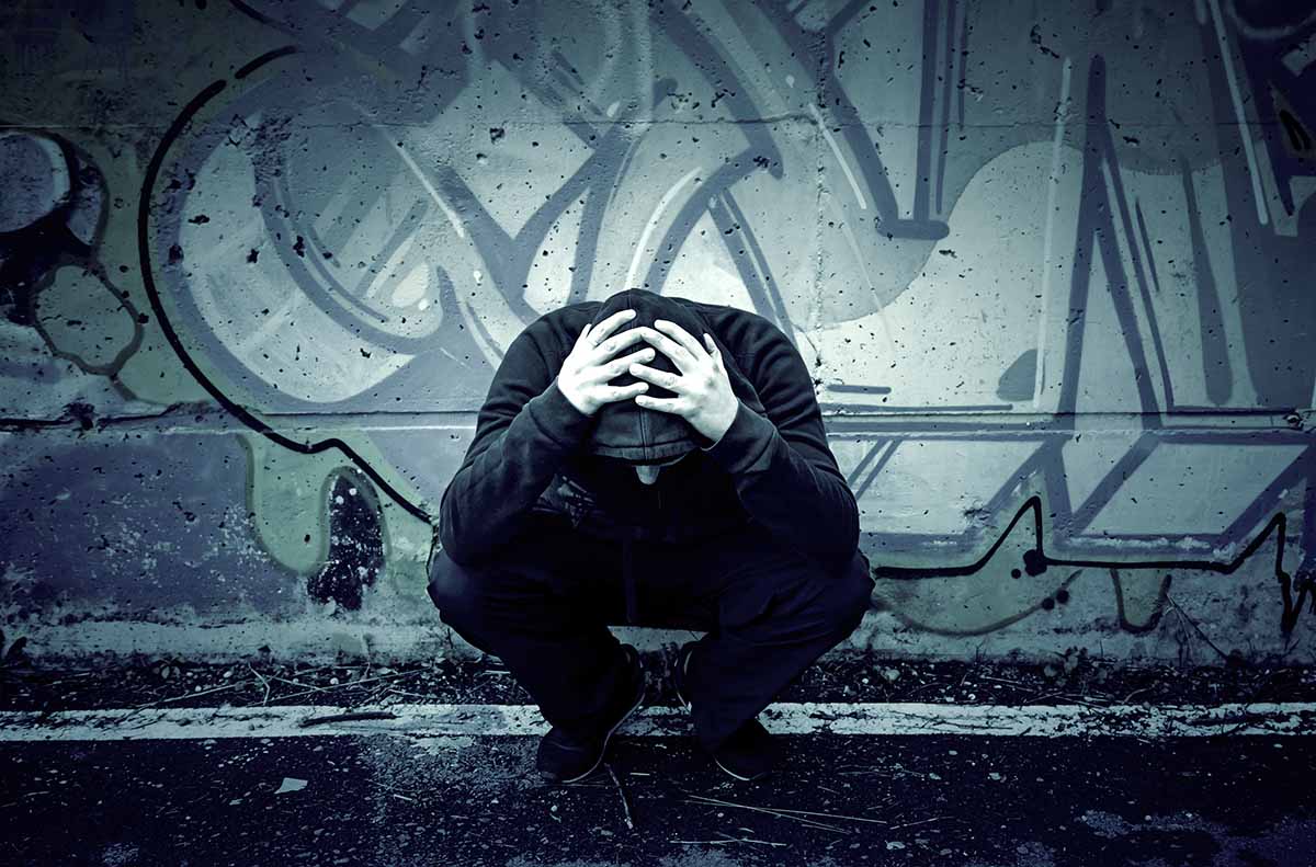 man crouched down holding head in alley worried about what are gateway drugs