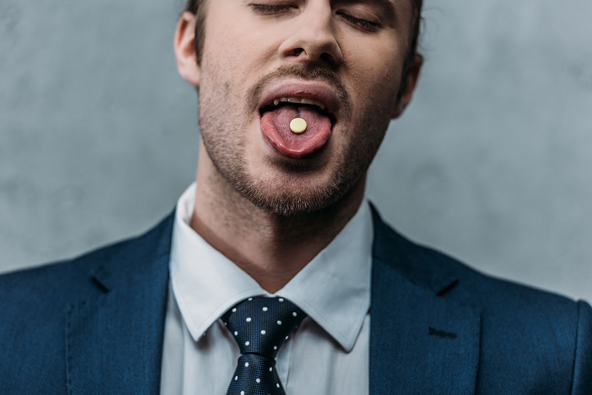 man euphoric with pill on tongue posing what is mdma