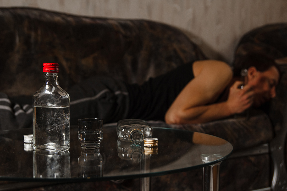 man passed out on couch with alcohol facing the Dangers of Binge Drinking