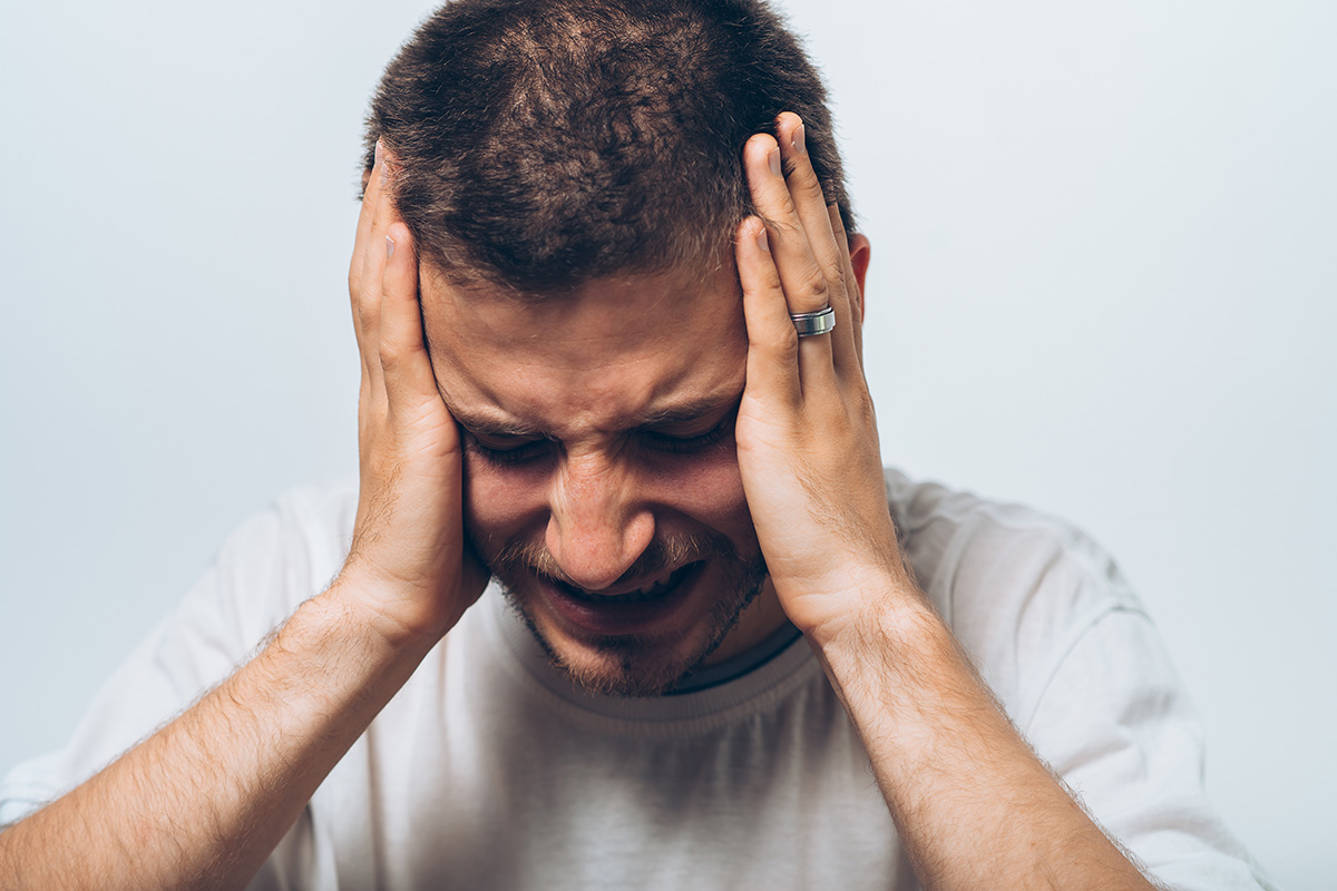man holding his head in pain from the Signs of a High Functioning Alcoholic