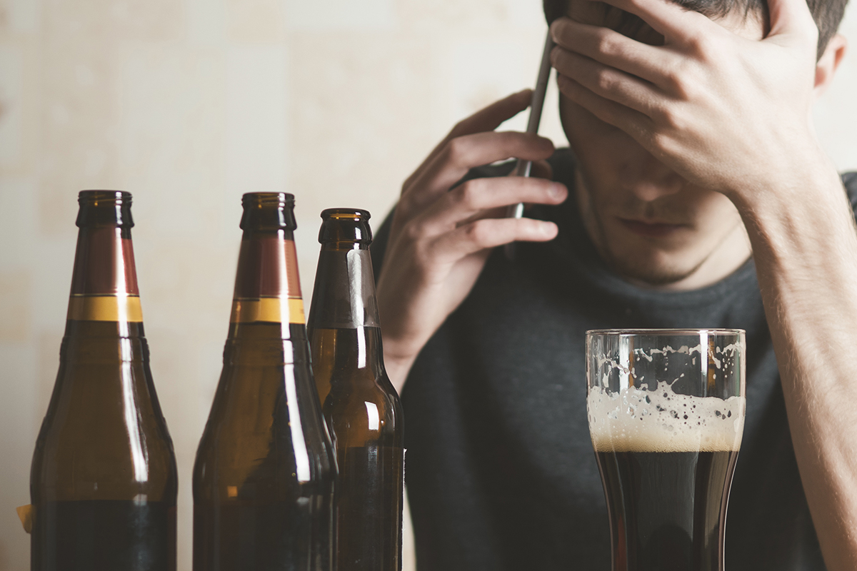 man surrounded by beer calling someone about Alcohol and Depression issues