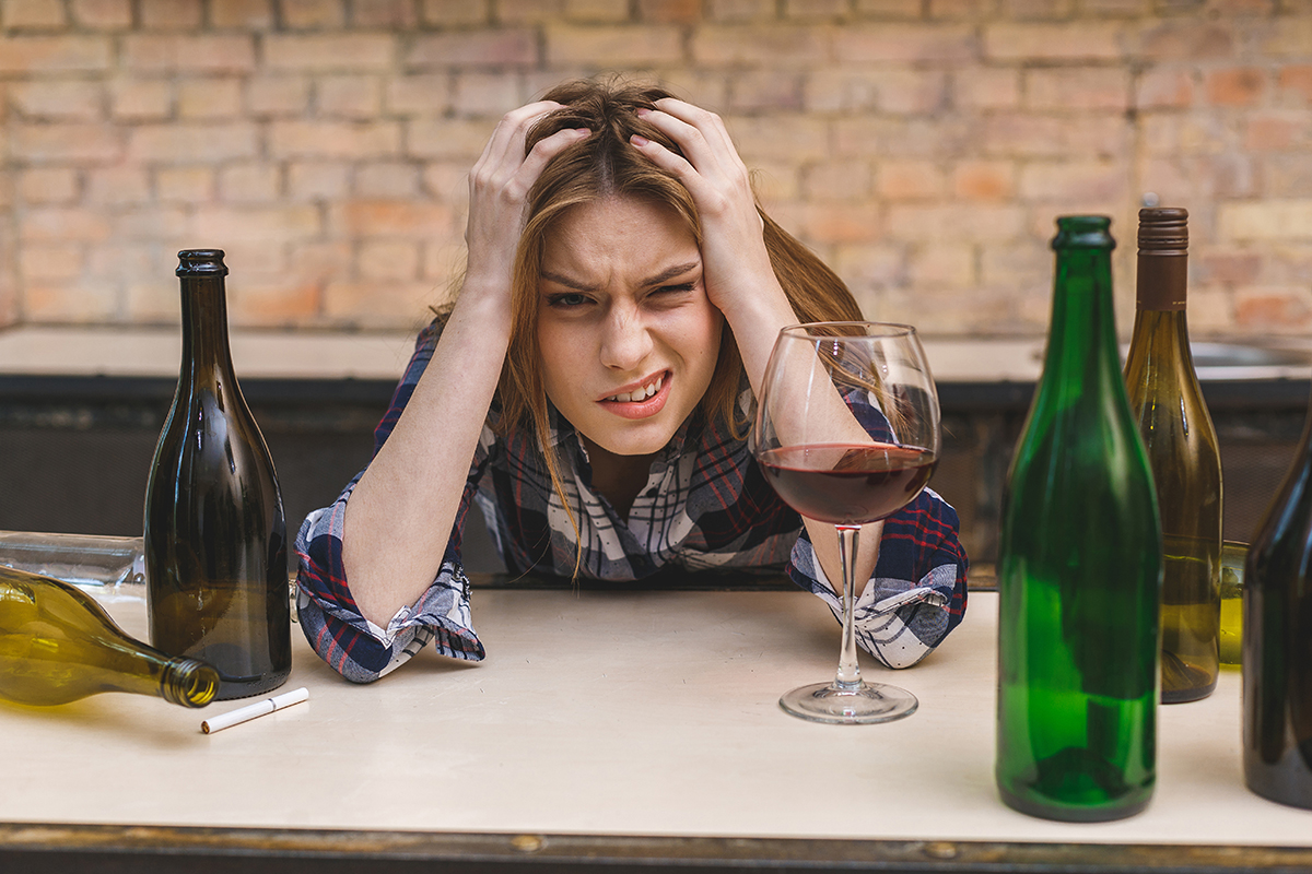 young woman struggling with the Alcohol Withdrawal Timeline surrounded by alcohol