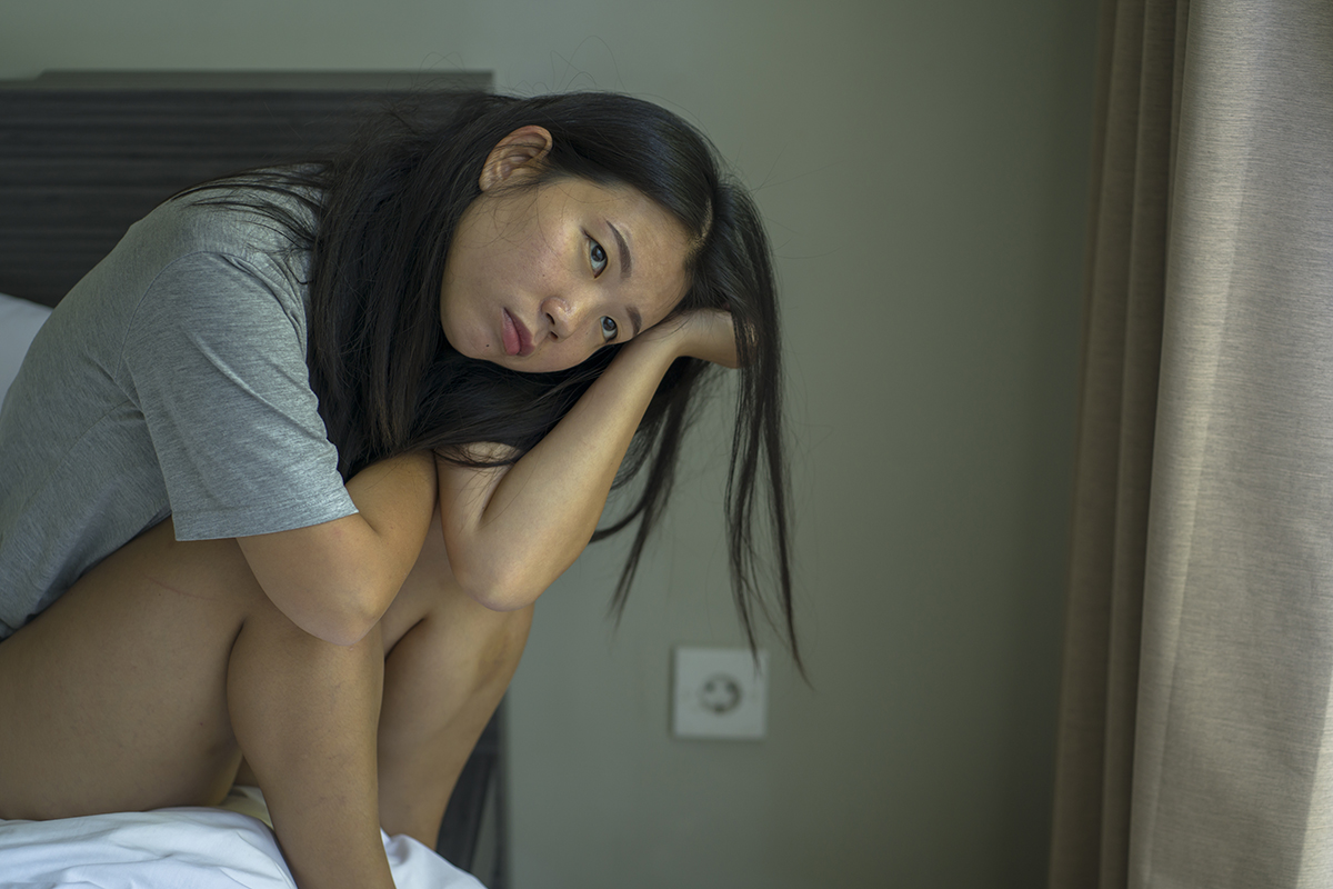 depressed woman leaning over in bed with Mental Health and Addiction disorders