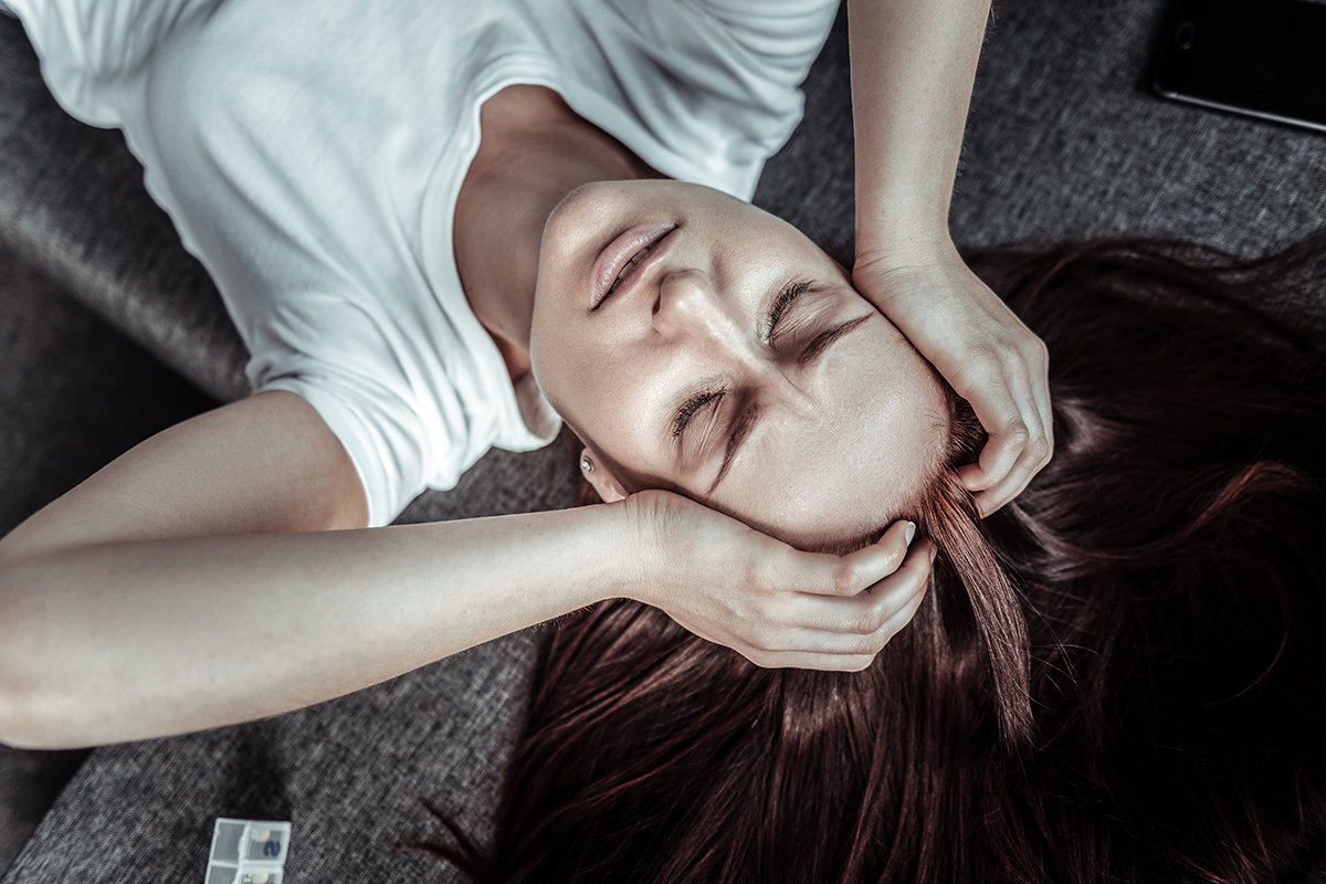 woman holding their head in pain from the Signs of a Heroin Addiction
