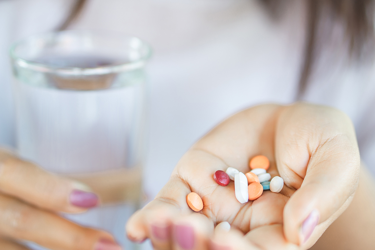 woman with multiple pills in hand showing Signs of Xanax Abuse