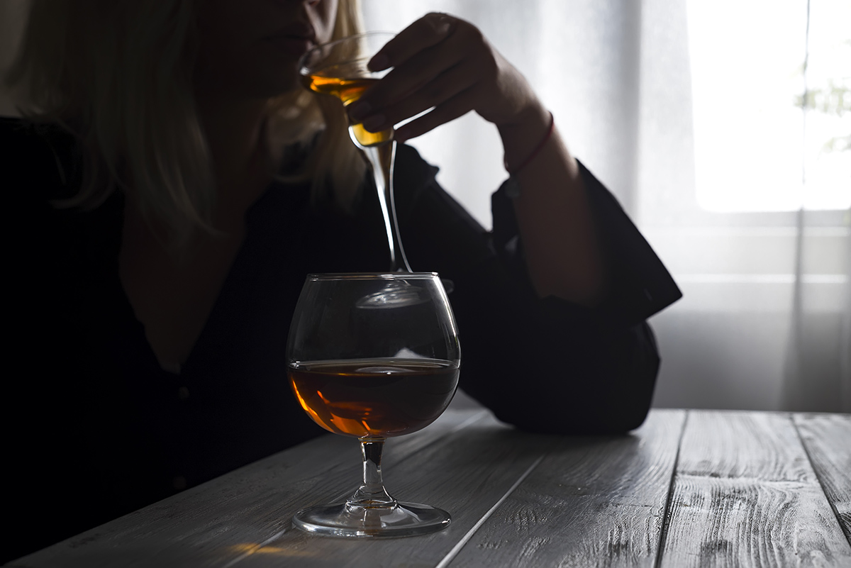 woman drinking in the shadows questioning Is Alcohol a Drug